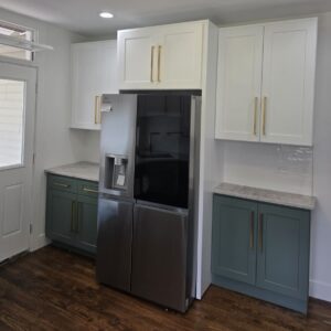 Remodeled kitchen with white upper cabinets, teal lower cabinets, brass hardware and a stainless steel refrigerator